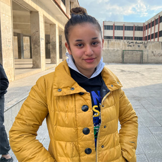 En jente på 16 år foran skolen sin i Syria