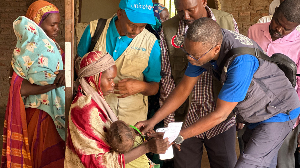 UNICEF-ansatt og helsepersonell undersøker et lite barn for underernæring i Sudan