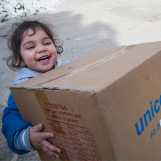 En jente bærer en UNICEF-eske, Syria