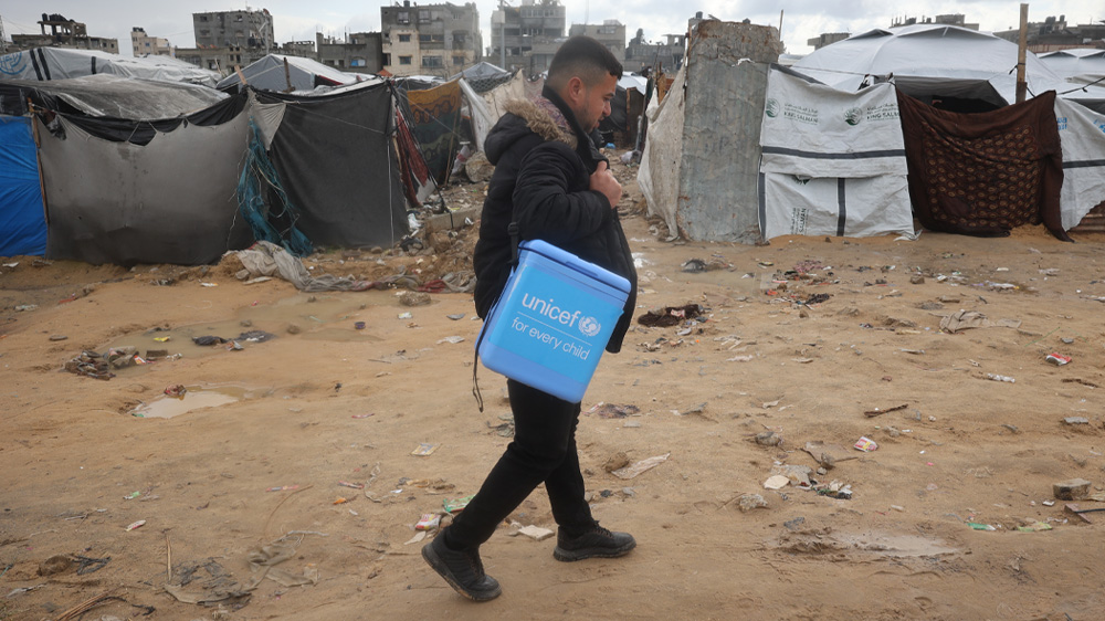 En UNICEF-ansatt går blant telt på stranden i Gaza