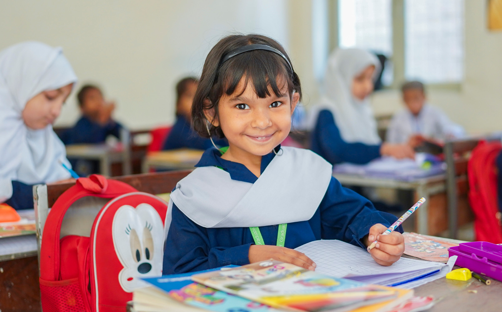 En jente sitter ved skolepulten og skriver, Pakistan