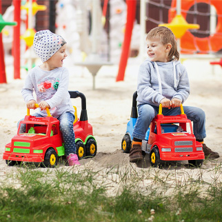 To barn sitter på lekebiler på en lekeplass