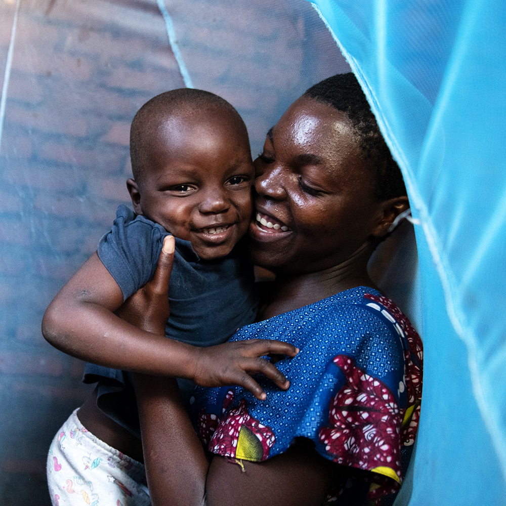 En mor holder barnet sitt under et myggnett, Malawi