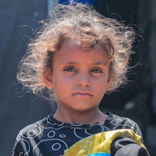 En jente står foran familiens telt i Gaza