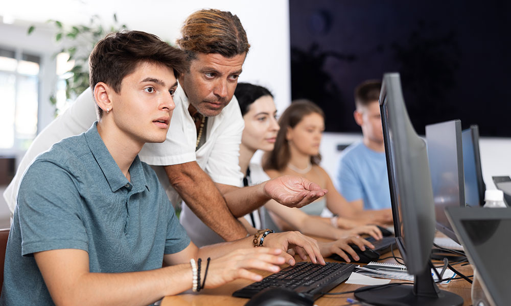 Elever og lærer foran pc