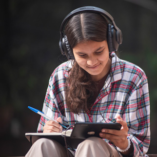 En ungdom sitter med et nettbrett og hodetelefoner, India