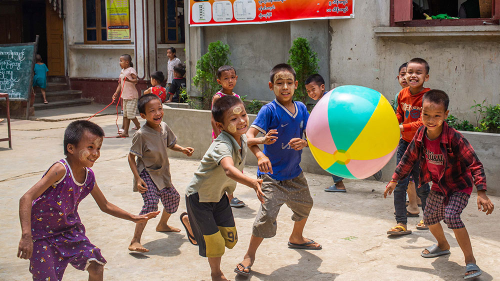 En gjeng med gutter leker med en badeball i gaten i Myanmar.