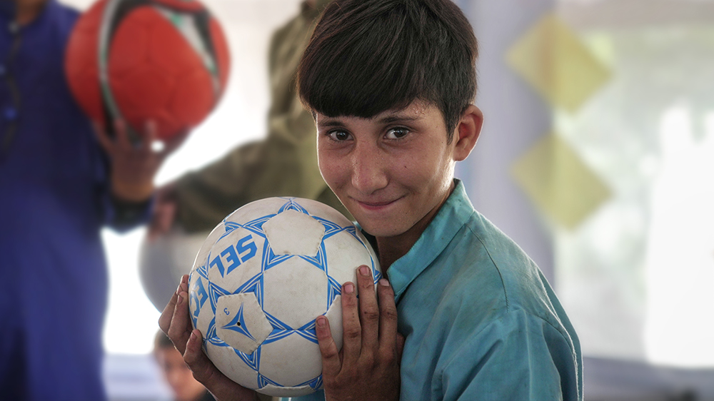 Omid (14) holder en fotball på et barnevennlig område støttet av UNICEF i Afghanistan. FOTO