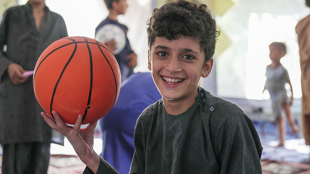 Sabawoon (9) holder en basketball etter å ha lekt med sine nye venner på et barnevennlig område støttet av UNICEF i Afghanistan. FOTO