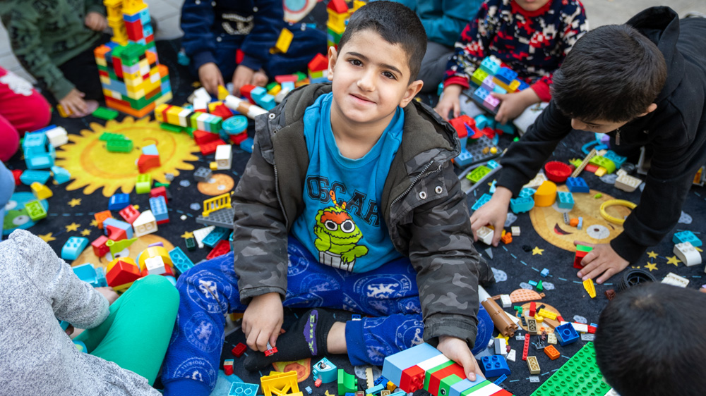En gutt sitter på et teppe fullt av lego, Libanon