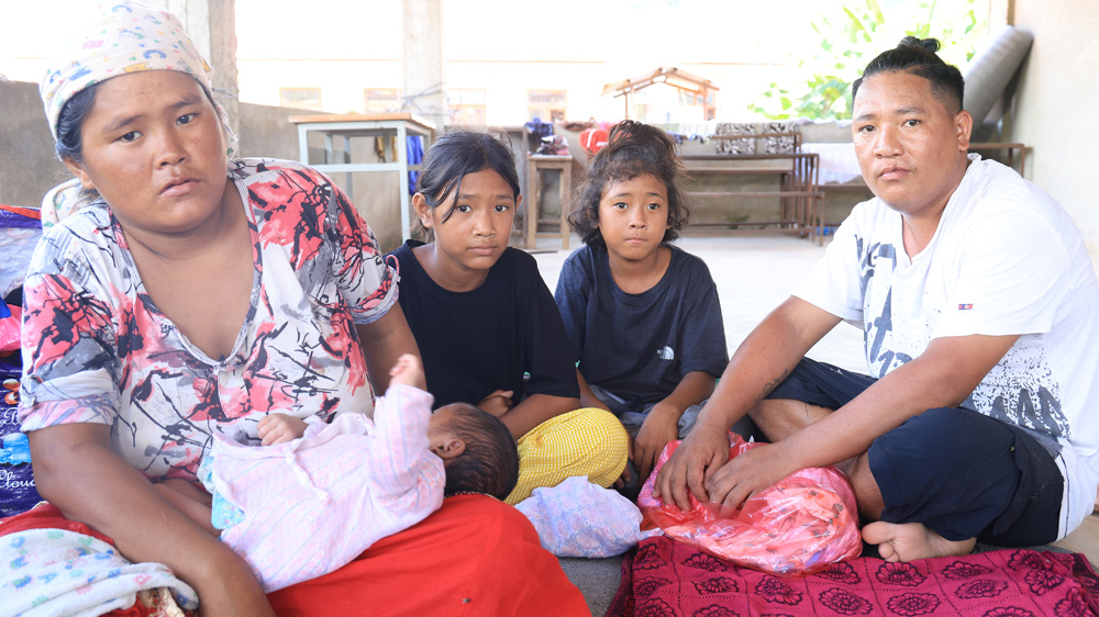 En familie som flyktet fra flommen i Nepal sitter sammen på en skole