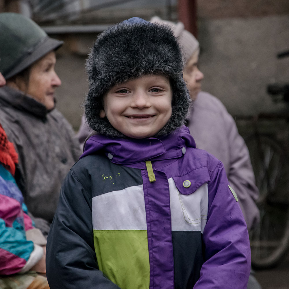 En gutt smiler til kamera og har på seg varme klær