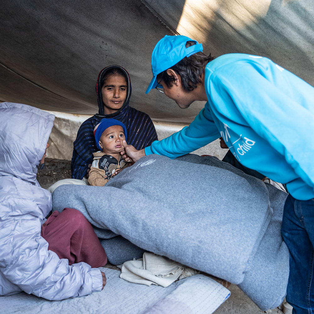 En familie får et varmt pledd av en ansatt i UNICEF