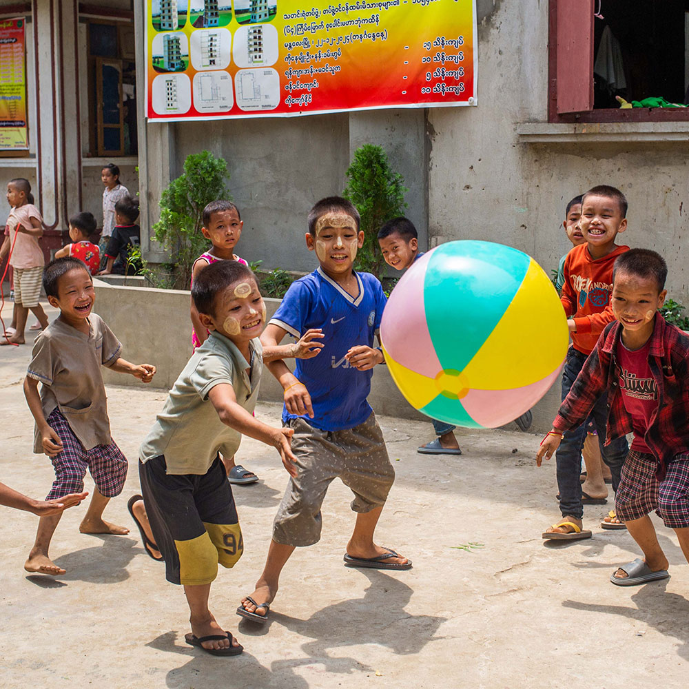 Barn leker med en badeball på gaten i Myanmar