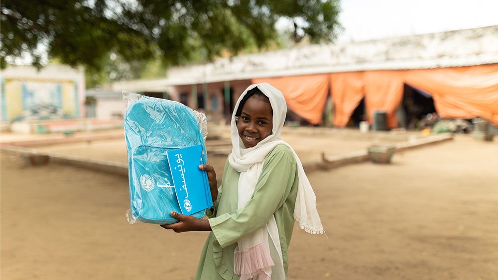 Et barn holder opp en skolesekk fra UNICEF.