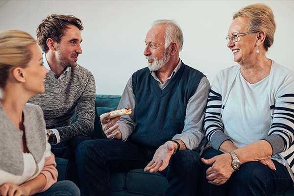 Et eldre og et yngre par sitter og prater lystig sammen.