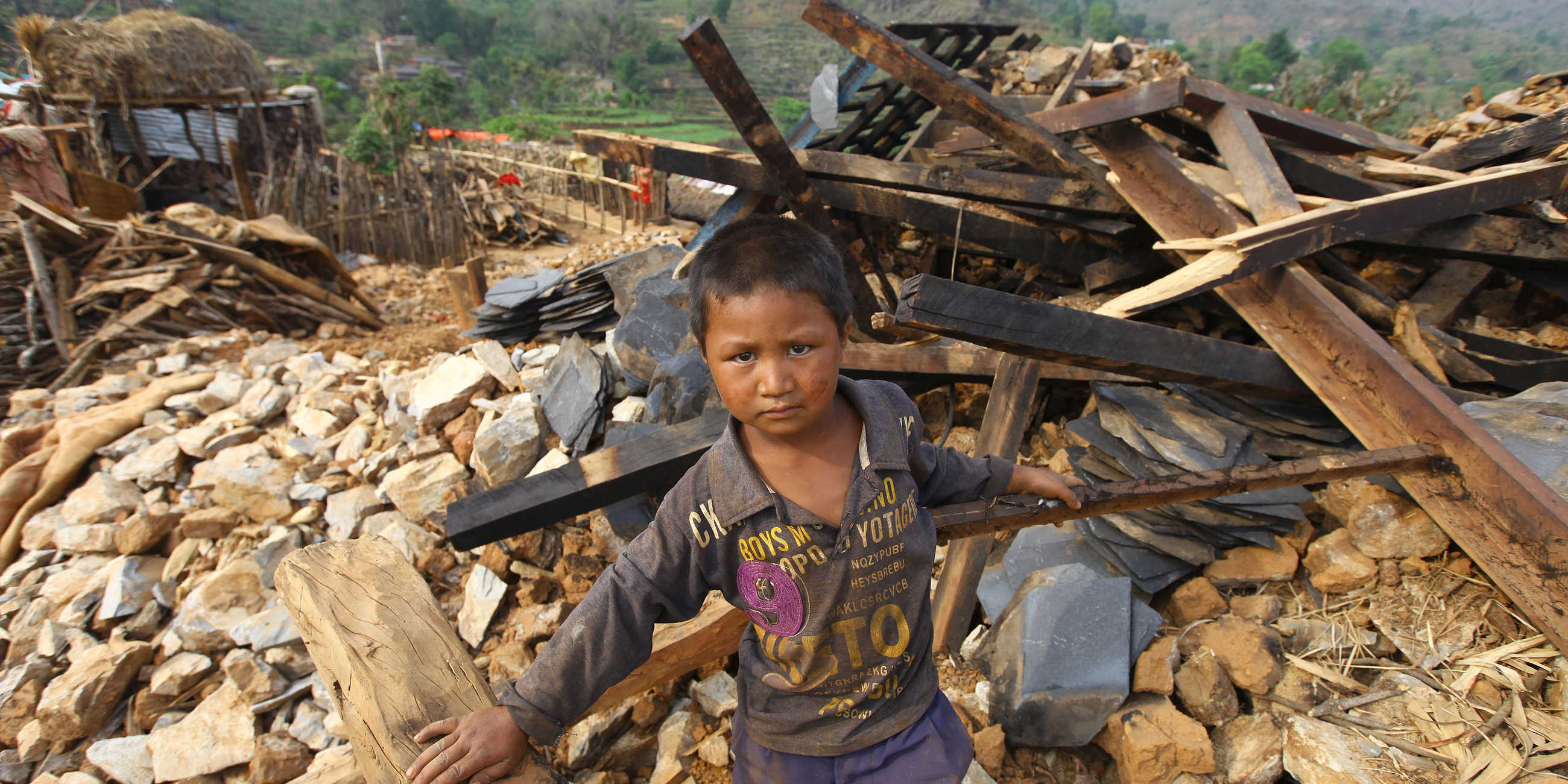 Gutt står utenfor ruinene av hjemmet sitt etter et jordskjelv i Nepal