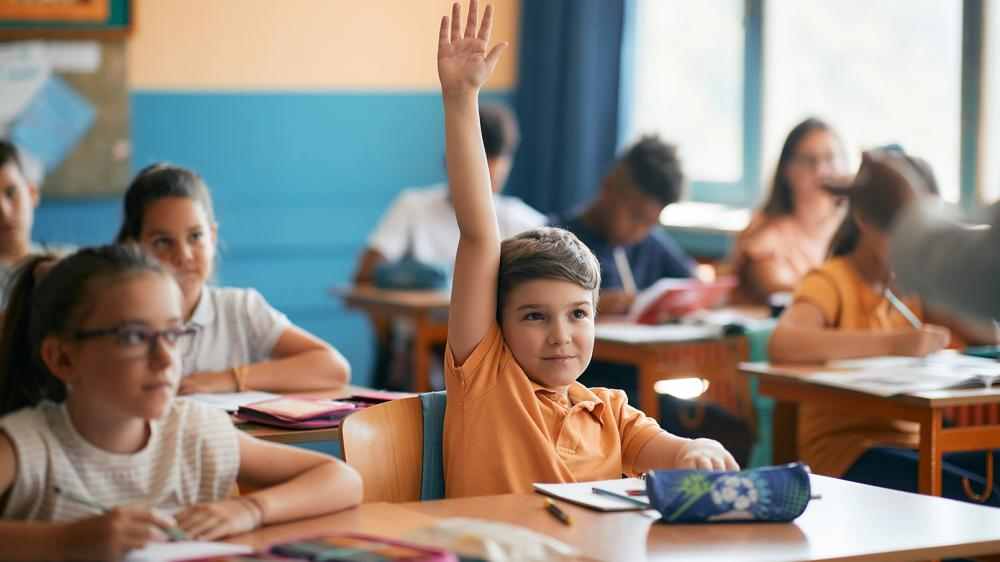 Gutt rekker opp hånden i klasserommet. FOTO