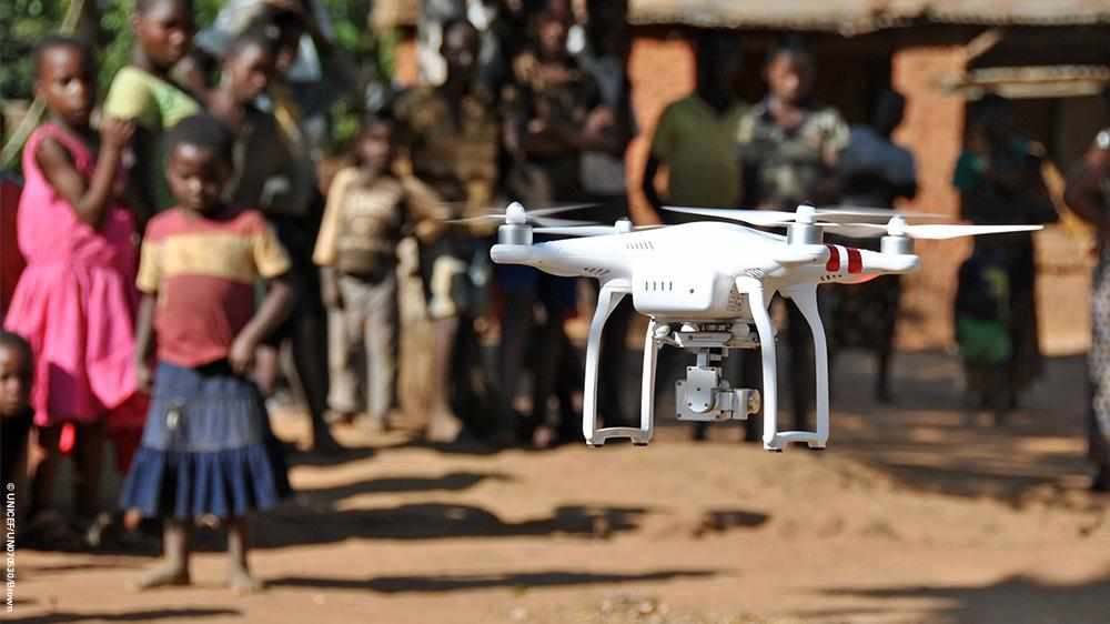 Drone flyr lavt med mennesker i bakgrunnen