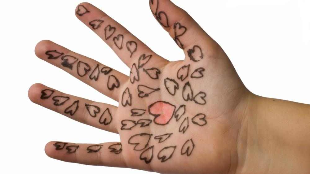 Bilde av hand med hjerter tegnet med tusj.