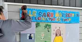 Gutt henger opp plakat med "rett til lek"