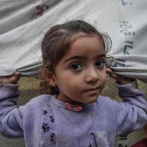 En jente står foran familiens telt i Gaza