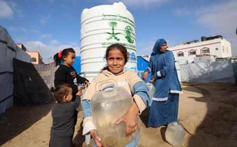 Jente på Gaza med vannkanne foran tank