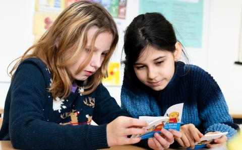 To jenter ser i bok på skolen