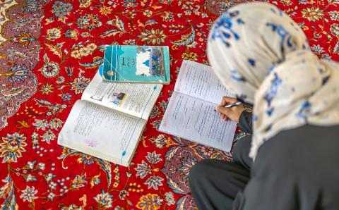 Afghansk jente leser på gulvet