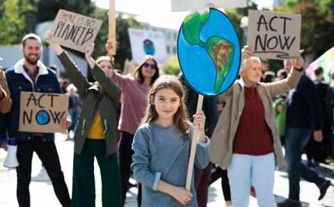 Jente holder plakat i demonstrasjon for klimaendringer. Foto