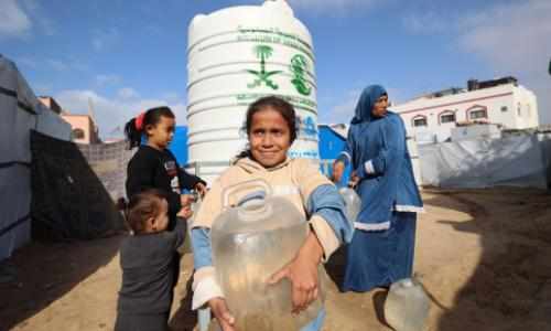 Jente på Gaza med vannkanne foran tank