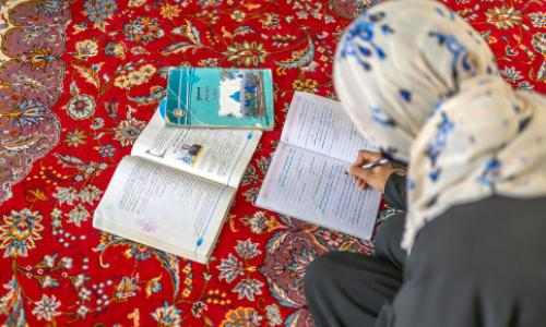 Afghansk jente leser på gulvet