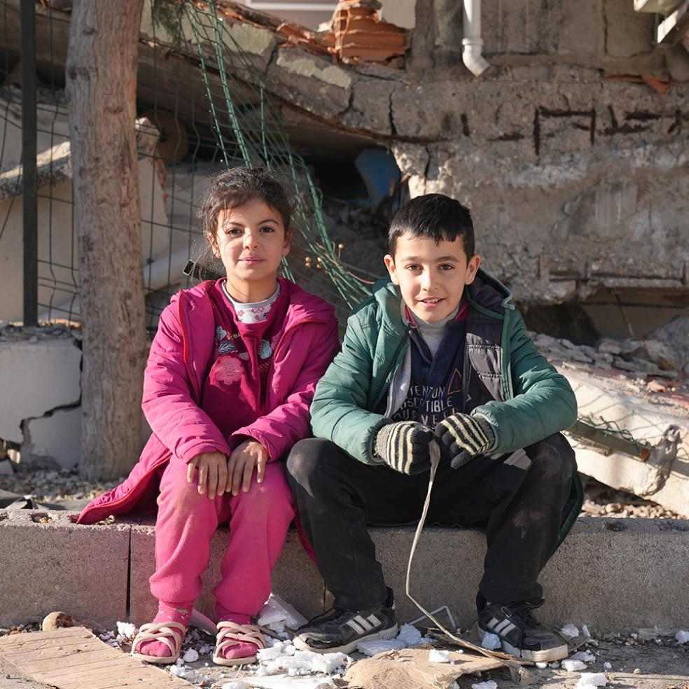 To barn sitter i ruiner etter jordskjelvet i Tyrkia i februar 2023