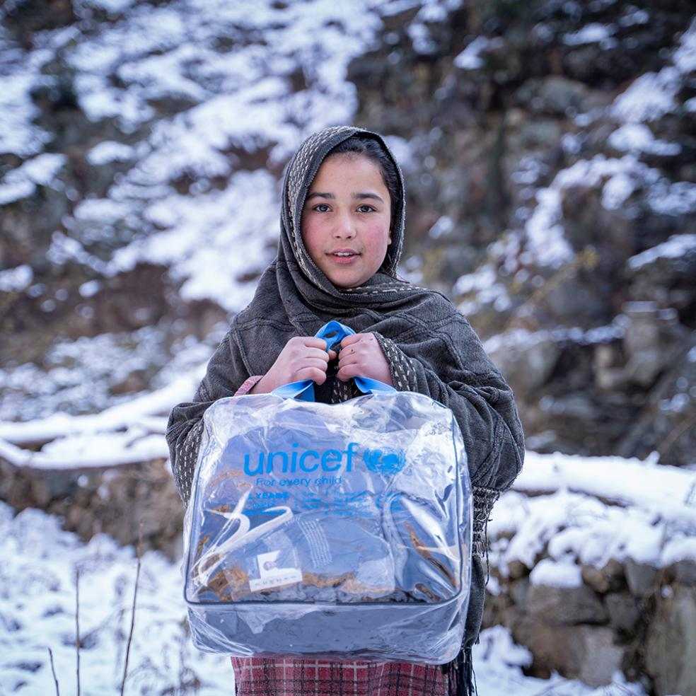 Gutt holder en sekk med varme klær levert fra UNICEF