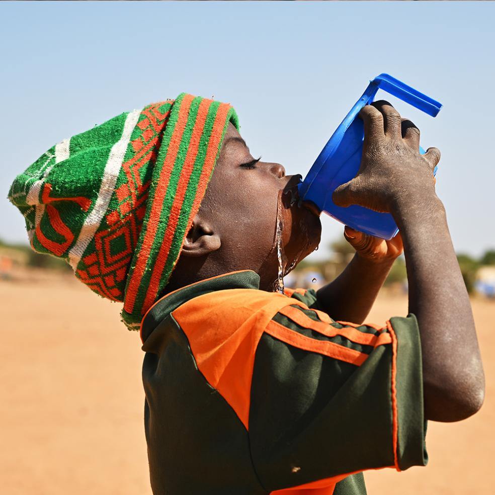 Et barn drikker vann av en blå kopp, Angola