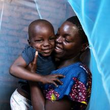 En mor holder barnet sitt under et myggnett, Malawi