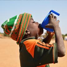 Et barn drikker vann av en blå kopp, Angola