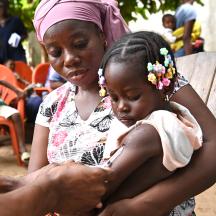 Mor som holder et barn som mottar vaksine